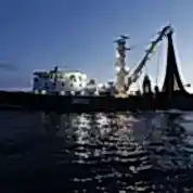 Industrial fishing vessel at dawn on calm waters.